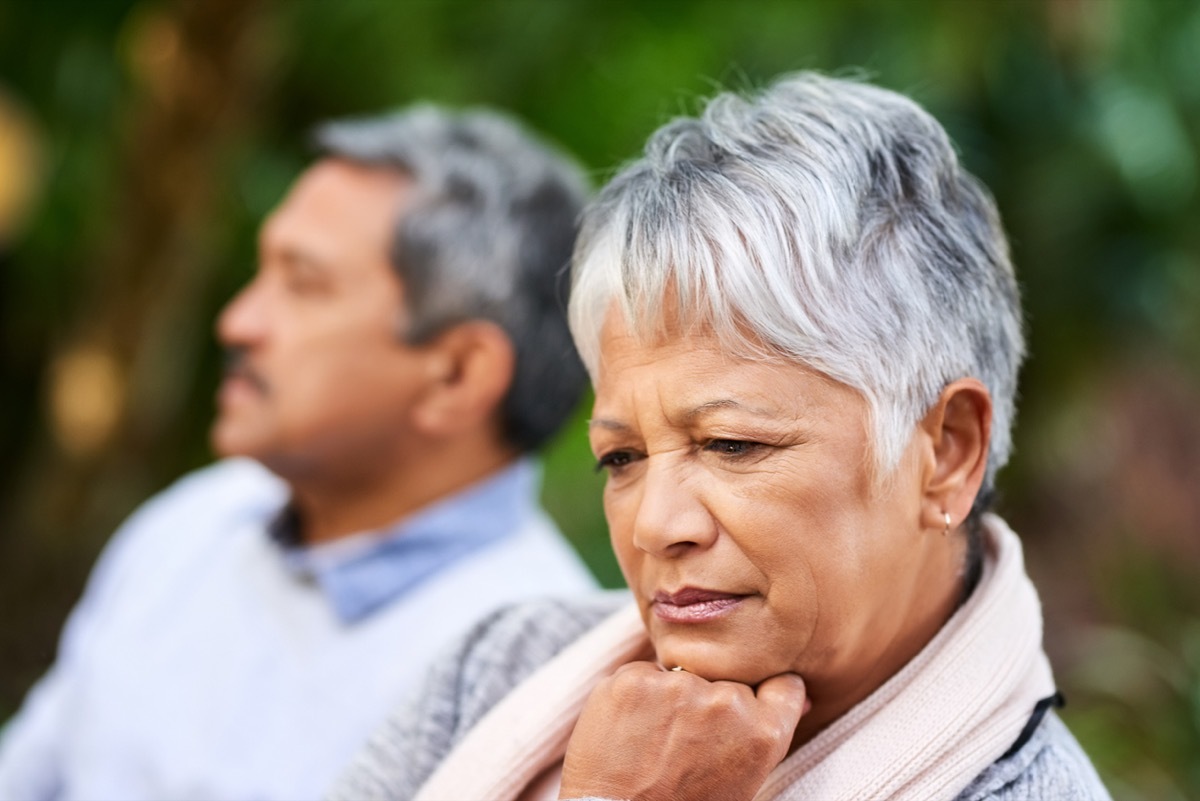 Shot of a senior woman of color looking upset with her husband in the background