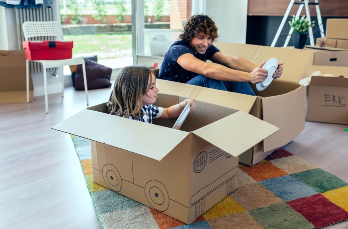 Father and son playing car racing with cardboard boxes in the living room