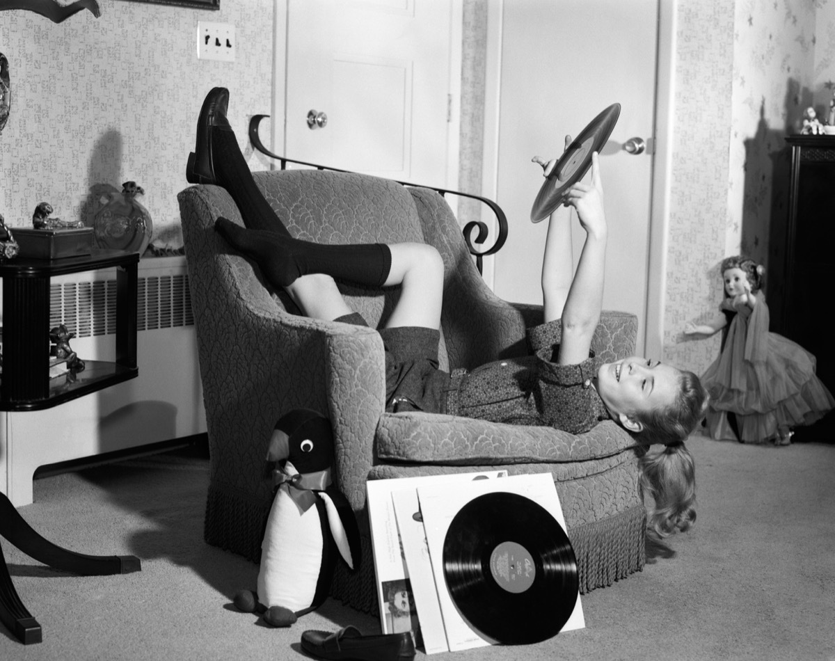 1960s teen girl sits upside down on chair, cool grandparent