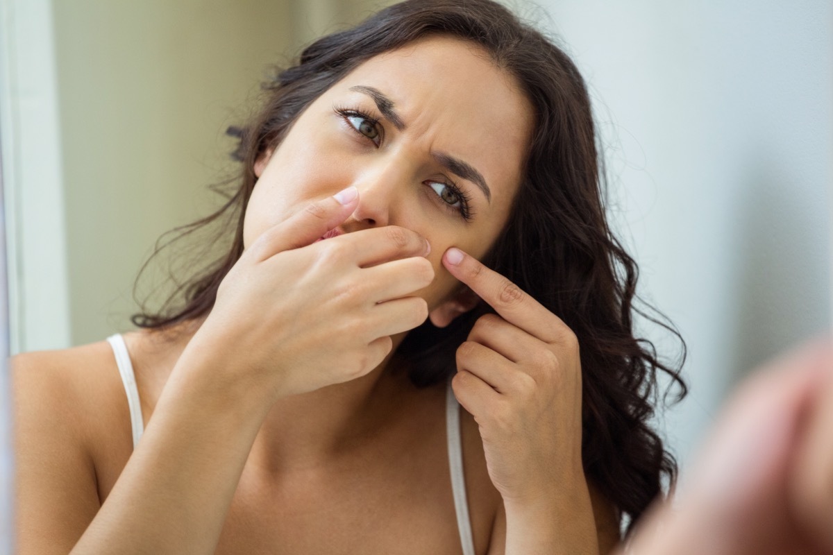 Woman popping her pimple in bathroom