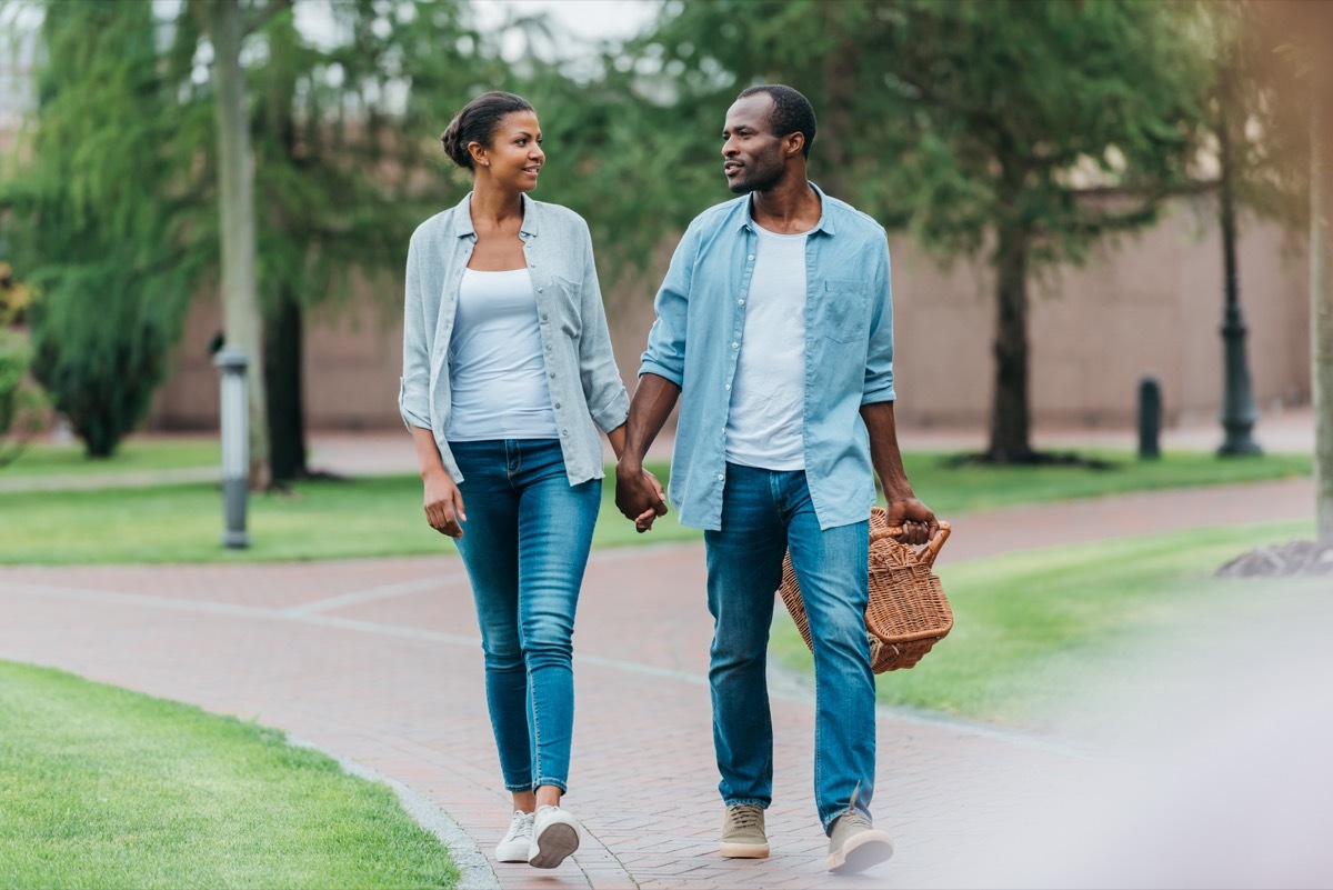 Couple walking in park together with a picnic basket