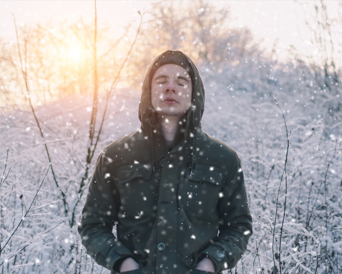 young man standing with his eyes closed in the snow