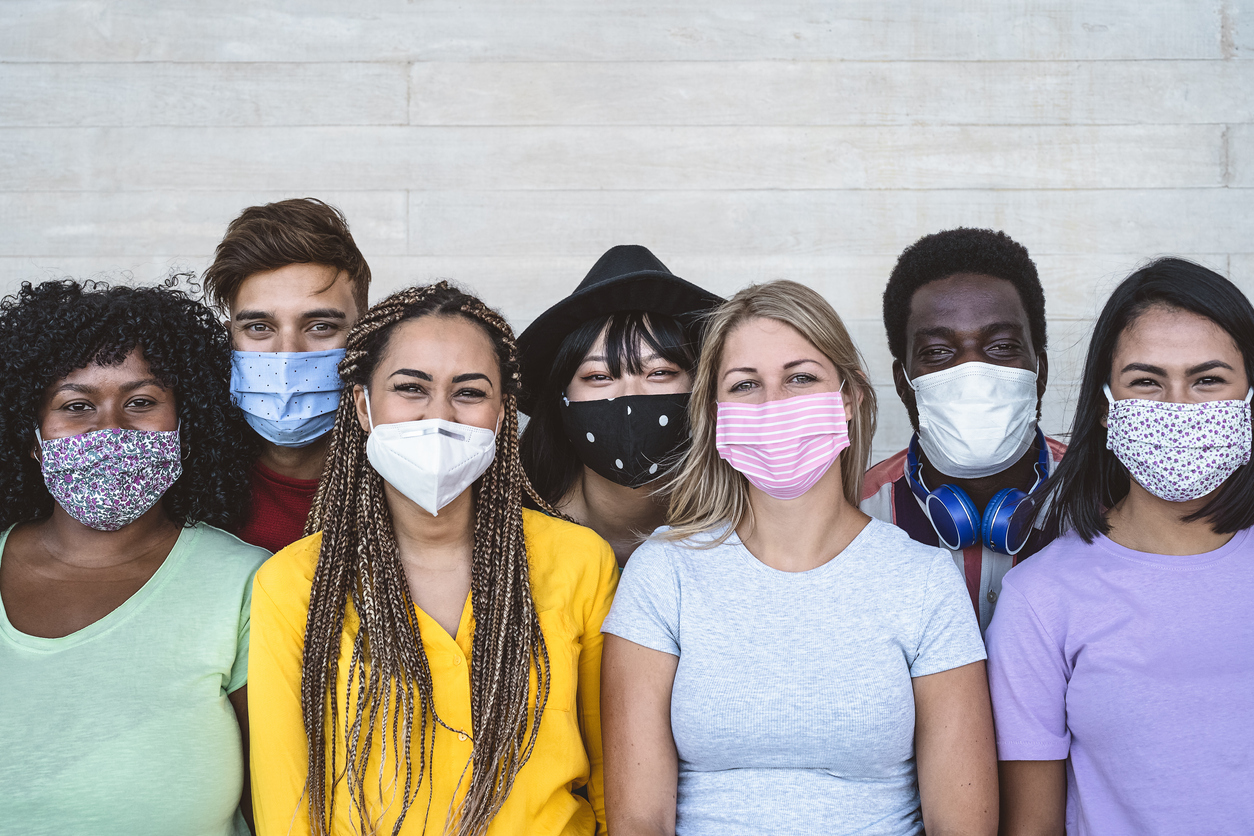 A group of multiethnic young people wearing different face masks and smiling.