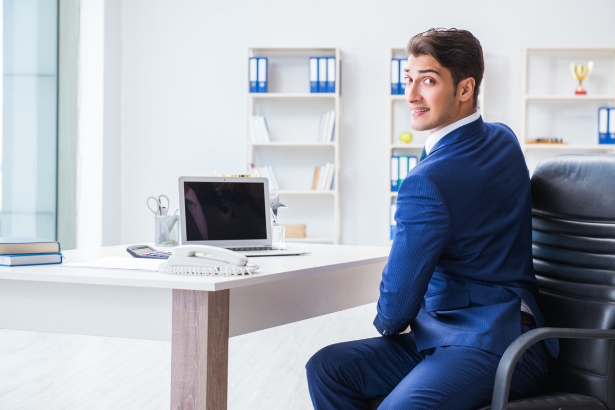 Young businessman doing sports stretching at workplace