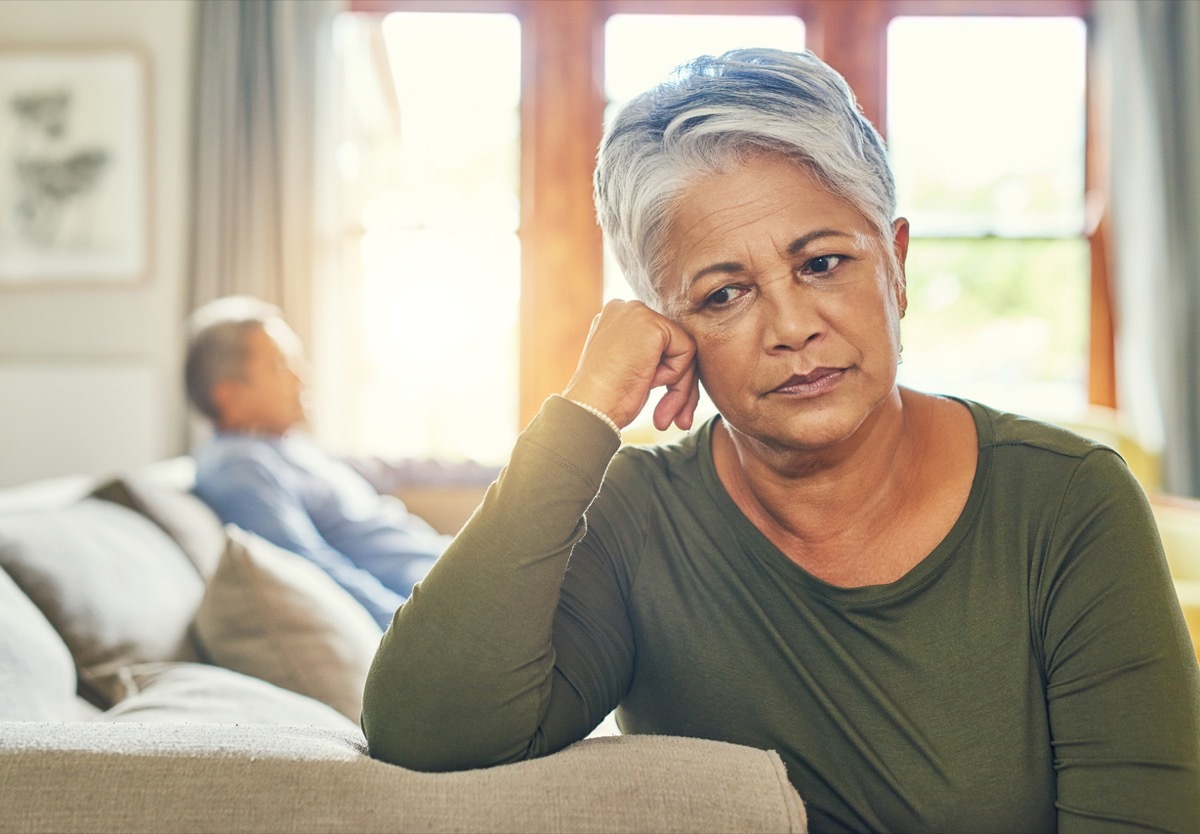 senior black couple sitting separately on a couch after having an argument