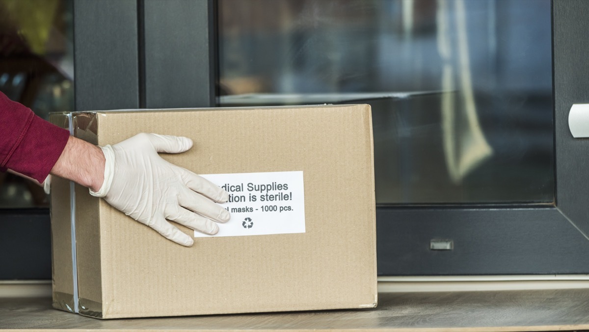 Courier brings a box with protective medical masks to the doorstep.