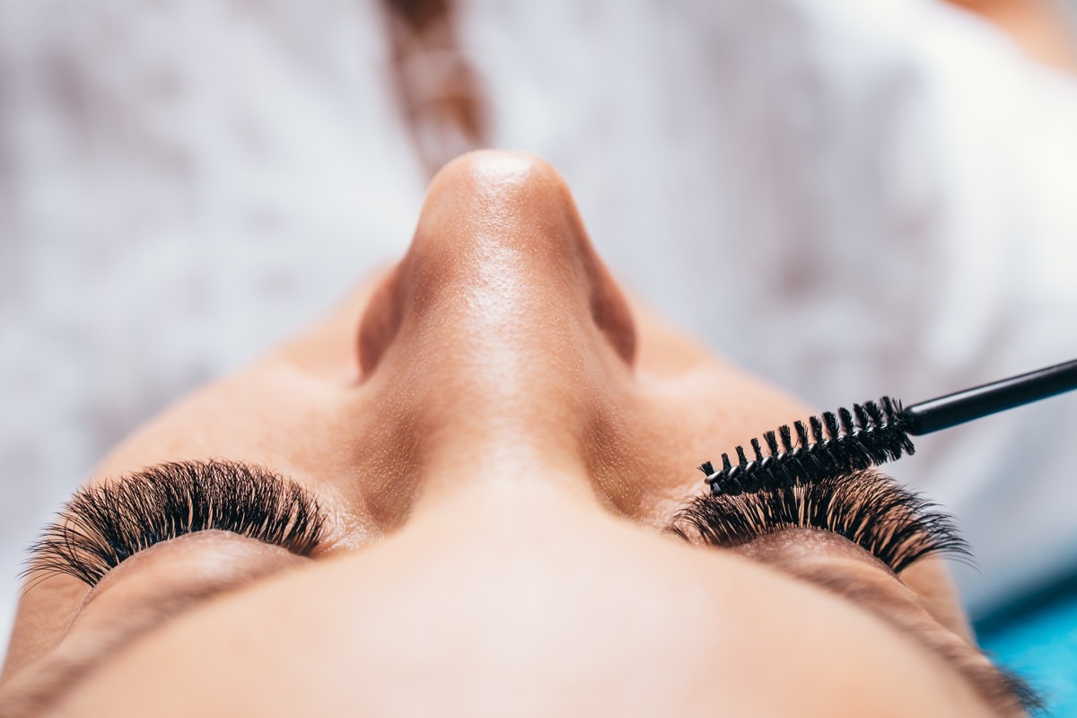 Woman applying mascara to lash extensions makeup