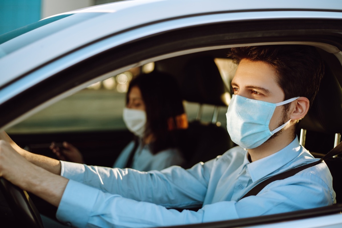 Man driving a car puts on a medical mask during an epidemic in quarantine city. Health protection, safety and pandemic concept. Covid- 19.