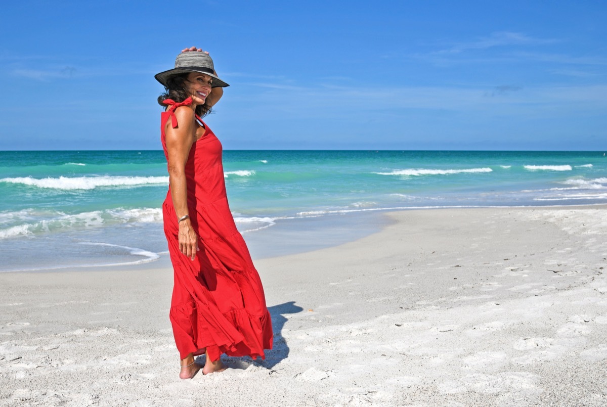 Beautiful Mature Woman Wearing a Red Summer Dress on the Beach