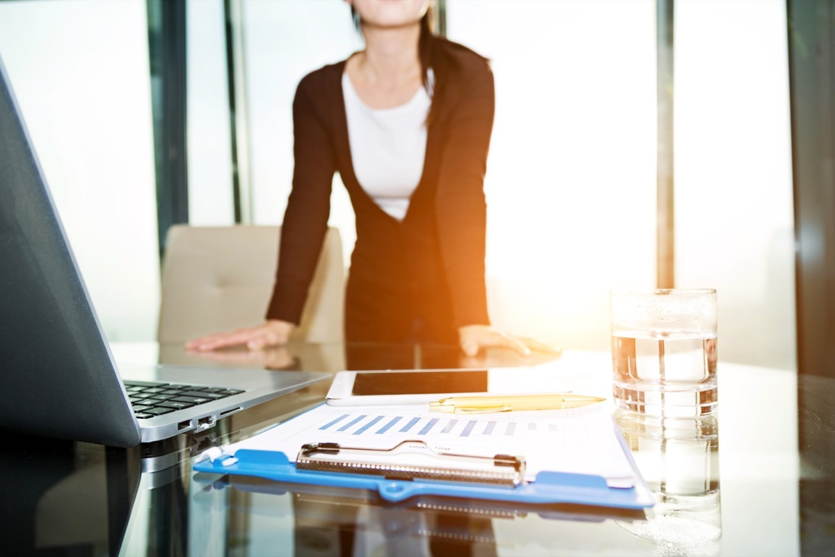 Stressed business woman standing and thinking in front of the office window office germs