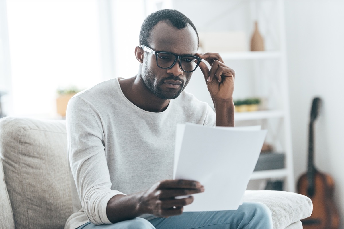 young man in glasses looking at paper