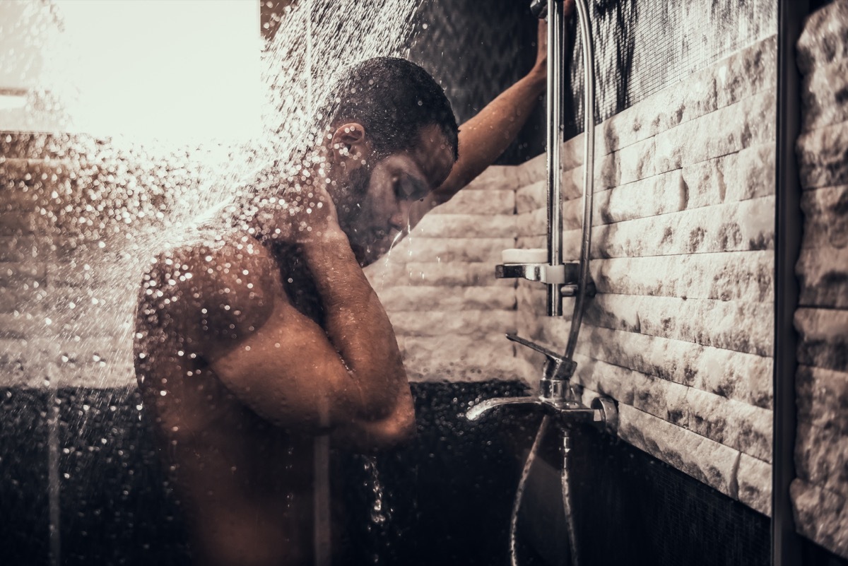 Man Taking Shower in Bathroom at Morning. Standing Man with Bare Torso in Bathroom. Personal Morning Routine. Fresh at Morning