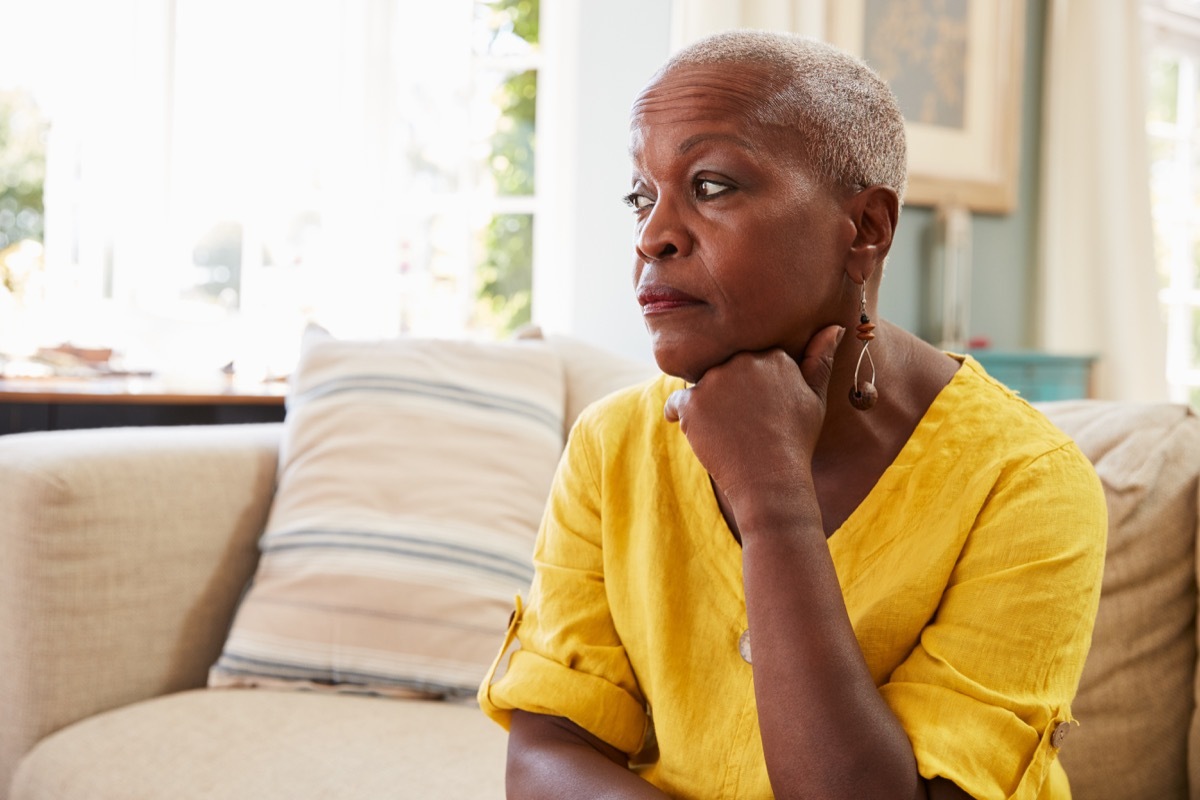 old worried woman sitting on the couch, single people