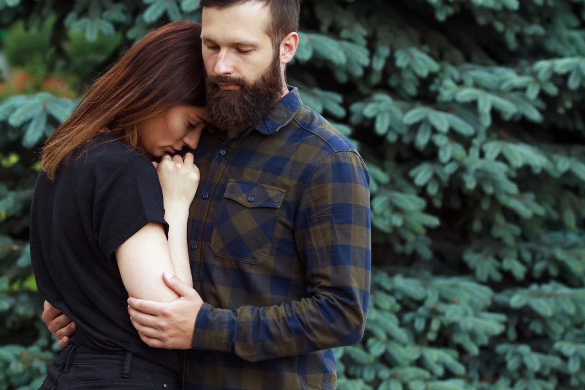 Man comforting sad woman in park