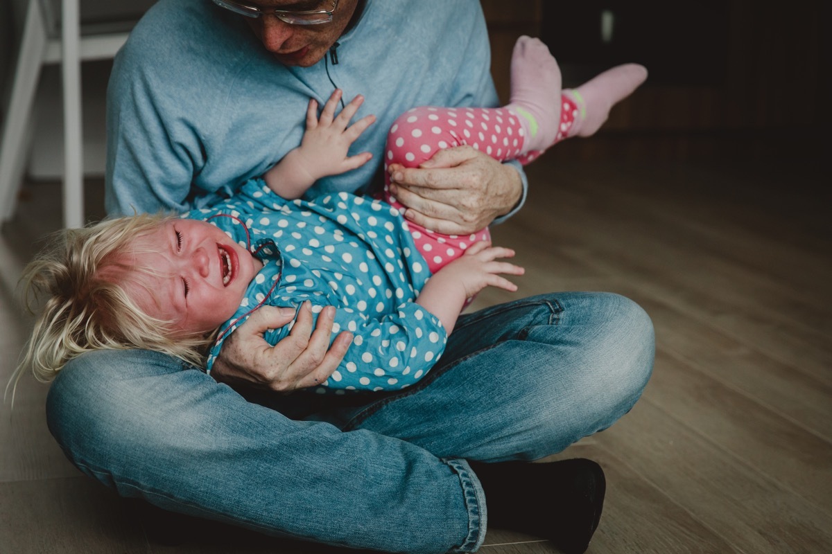 difficult parenting - dad trying to comfort shouting crying child, tired and exhausted father