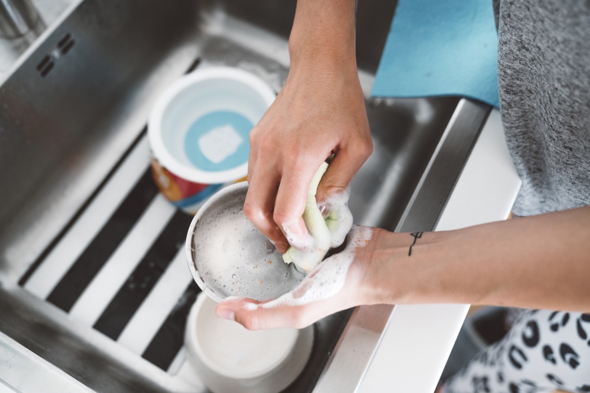 Unrecognizable woman hands washing dog bowl in the kitchen sink.