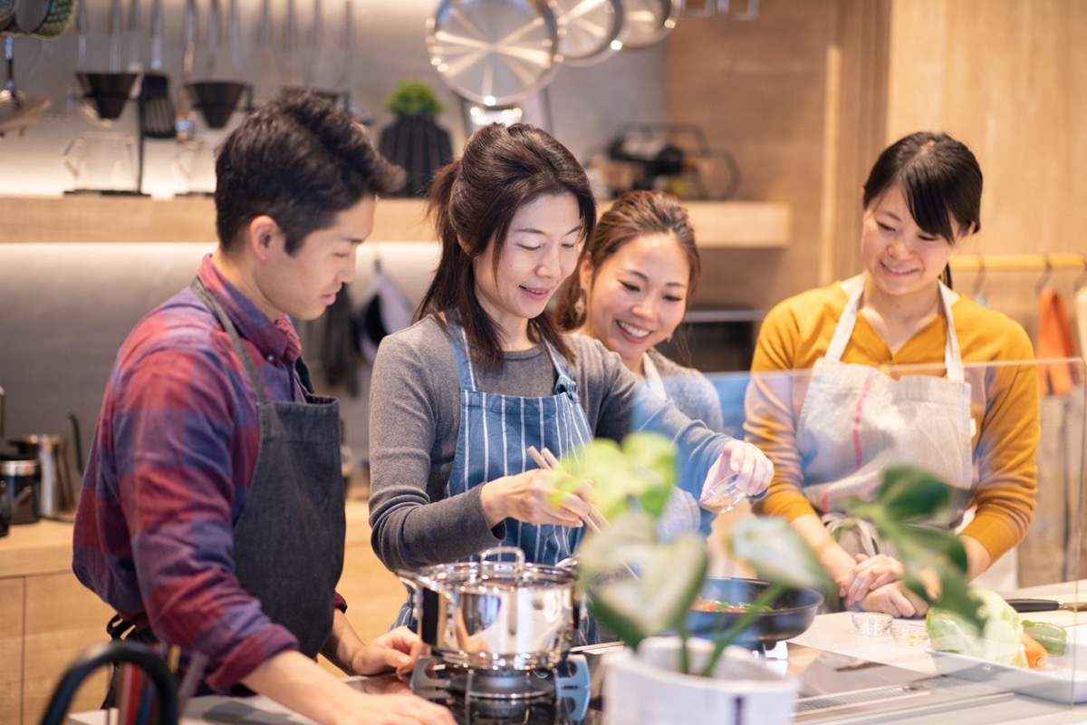 asian teacher and students making food at cooking class