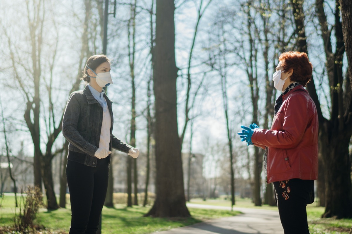 Elderly woman with protective face mask/gloves talking with a friend