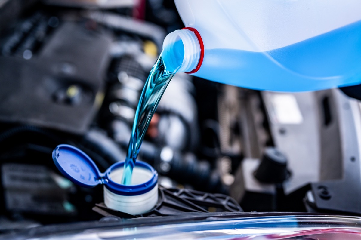 Pouring antifreeze. Filling a windshield washer tank with an antifreeze in winter cold weather.