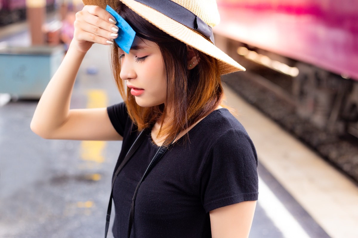 woman with hand on head, appearing faint