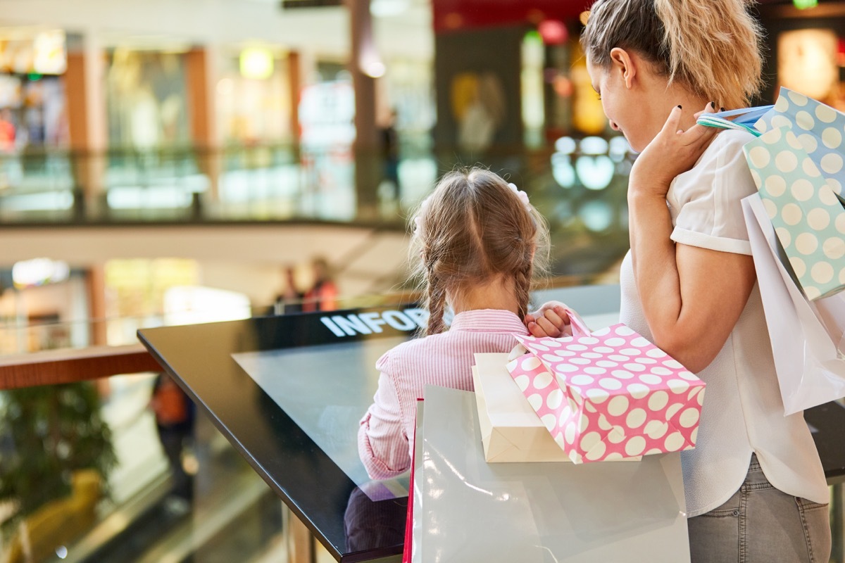 little girl looking at a mall directory with her mother