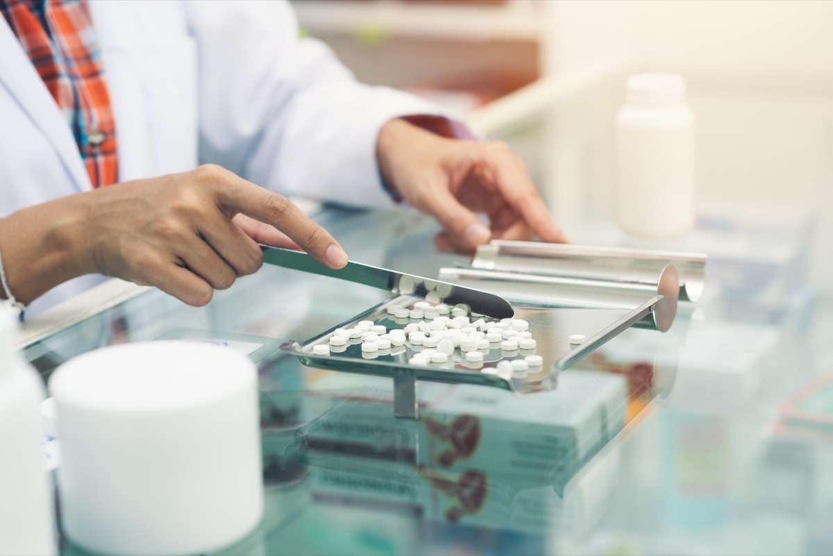 Medicine tablets on counting tray with counting spatula at pharmacy.