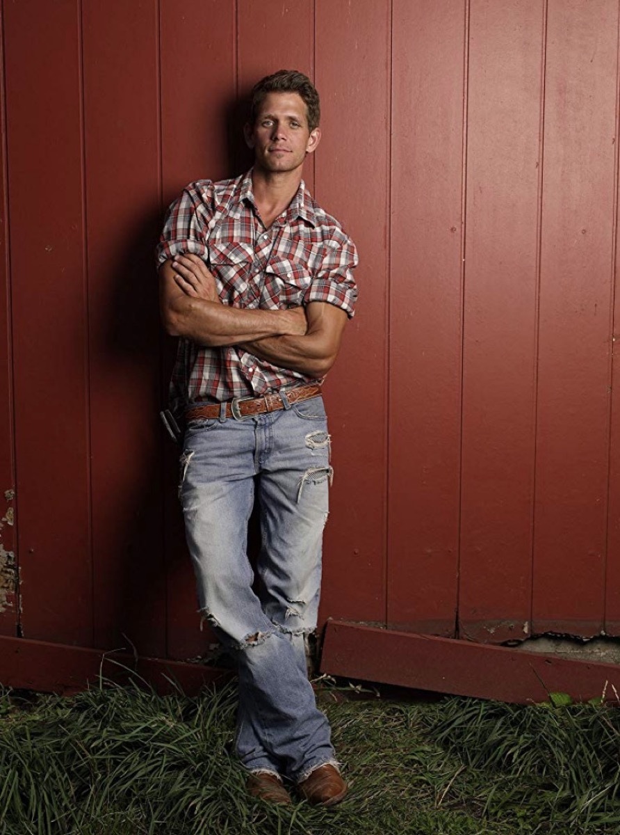 man in flannel standing against red wall