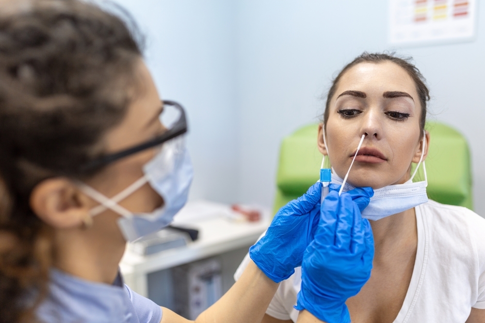 A young woman having her nose swabbed for a COVID test by a healthcare worker