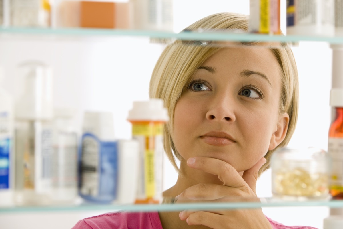 young woman looking in medicine cabinet