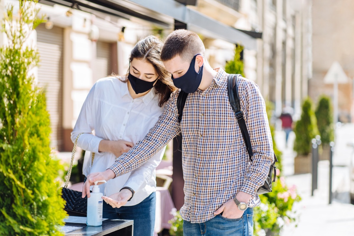 People wearing masks using hand sanitizer during COVID