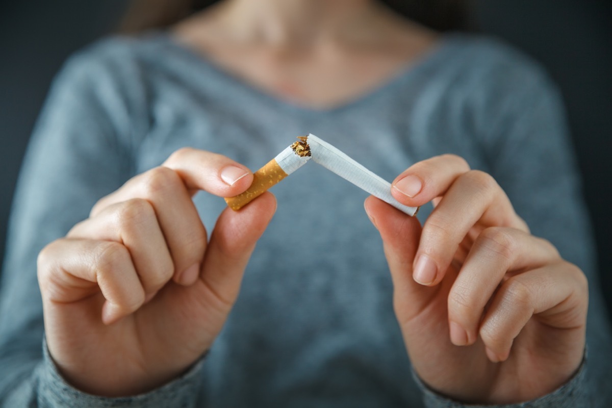 close up of white woman's hands breaking a cigarette in half