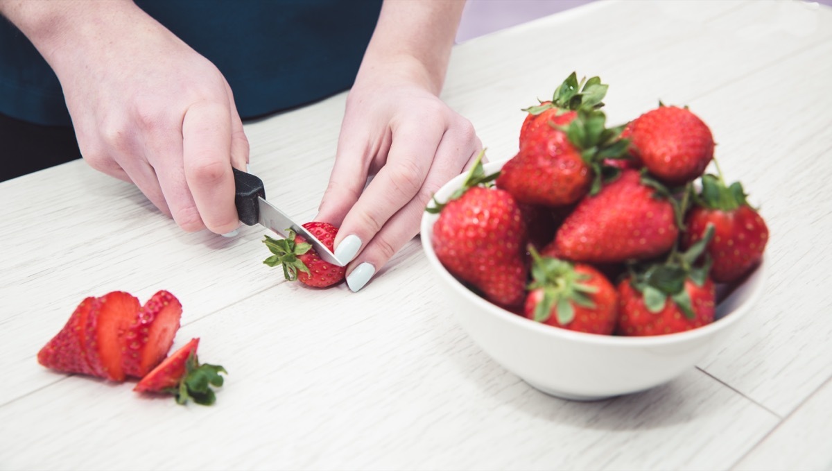 cutting off strawberry top with a knife, using objects wrong