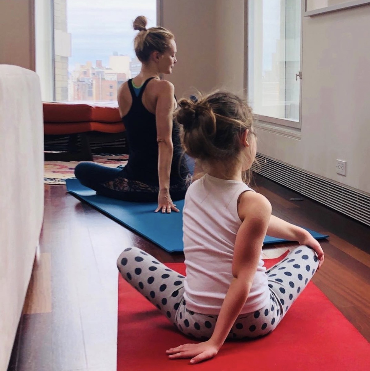 heather graham with her back to the camera doing yoga with a child